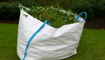 Green waste collection Perth – large white garden bag filled with grass clippings and leaves on a lawn for eco-friendly disposal.
