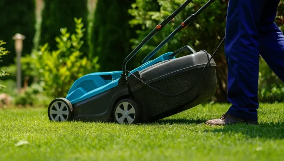 Worker mowing lawn as part of the best garden clean up services, keeping the grass neat and the garden well-maintained.