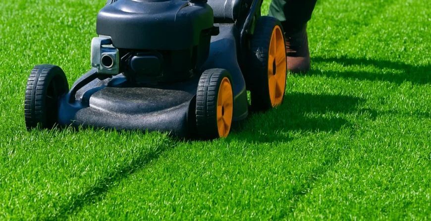 Professional yard cutting service with a worker mowing green grass using a lawn mower on a well-maintained lawn